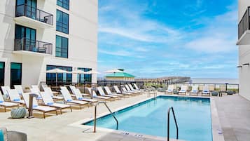 A poolside area with lounge chairs and a view of the ocean.