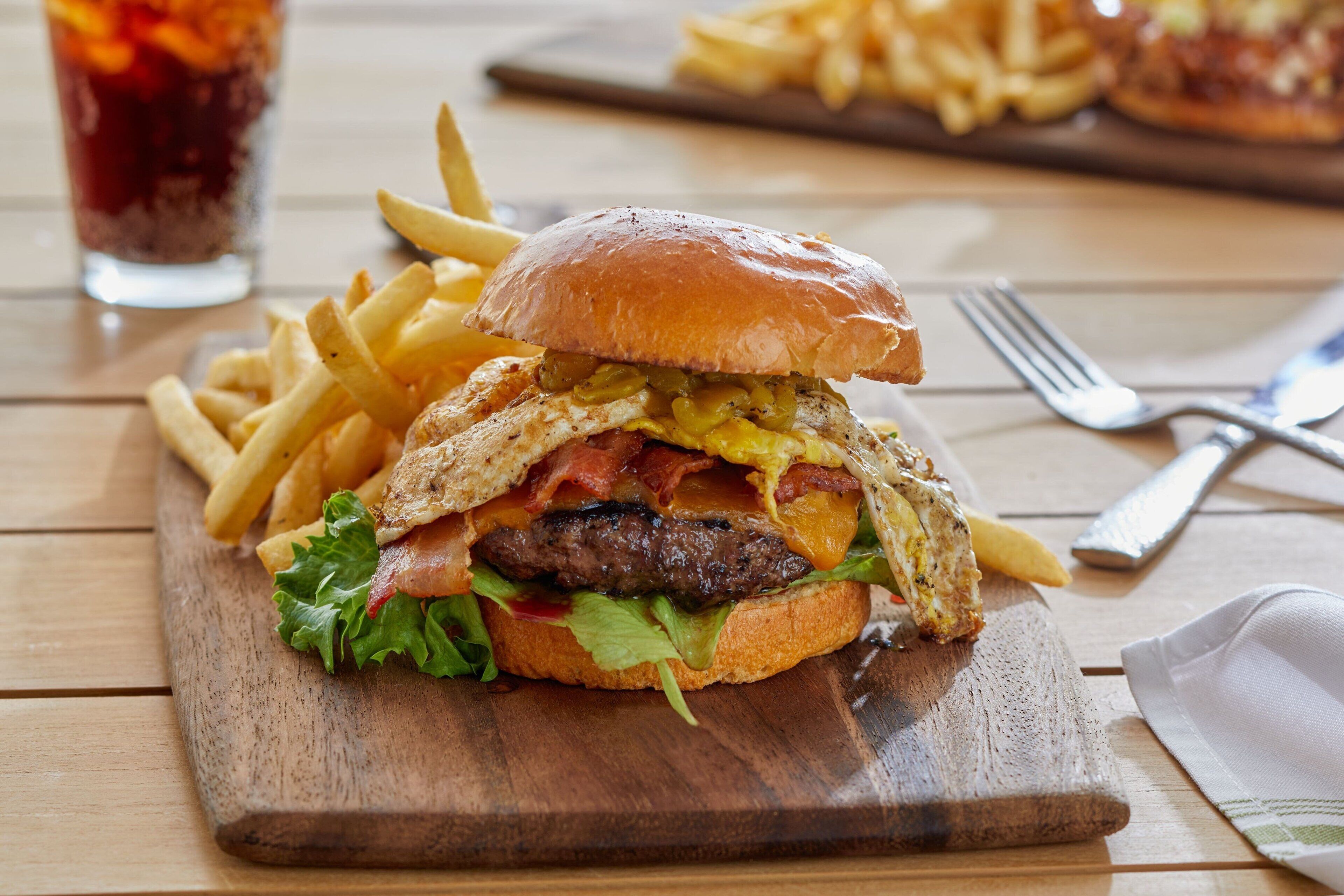 A burger with fries on a wooden board.
