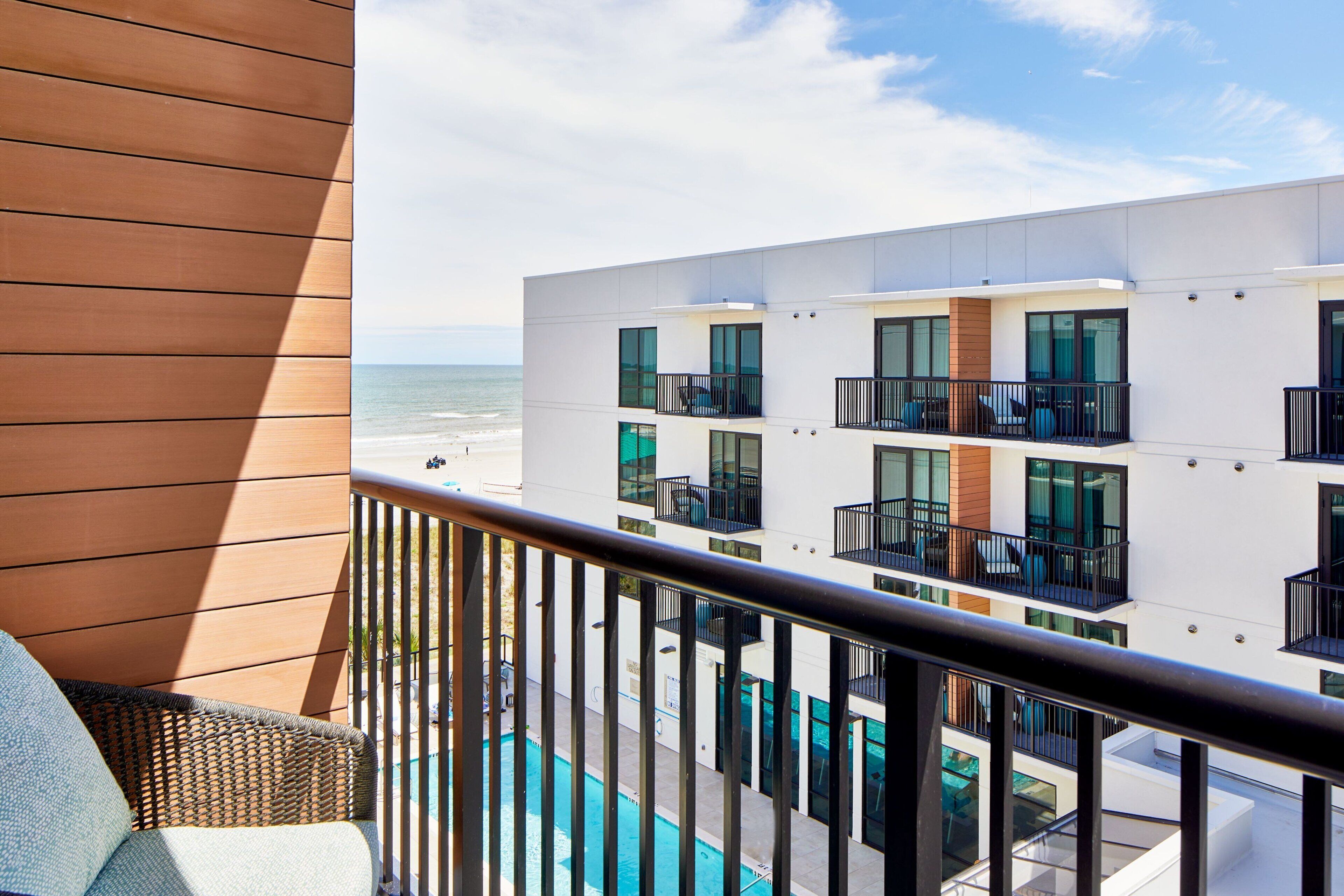 Un bâtiment moderne doté de balcons donnant sur une piscine et l’océan.