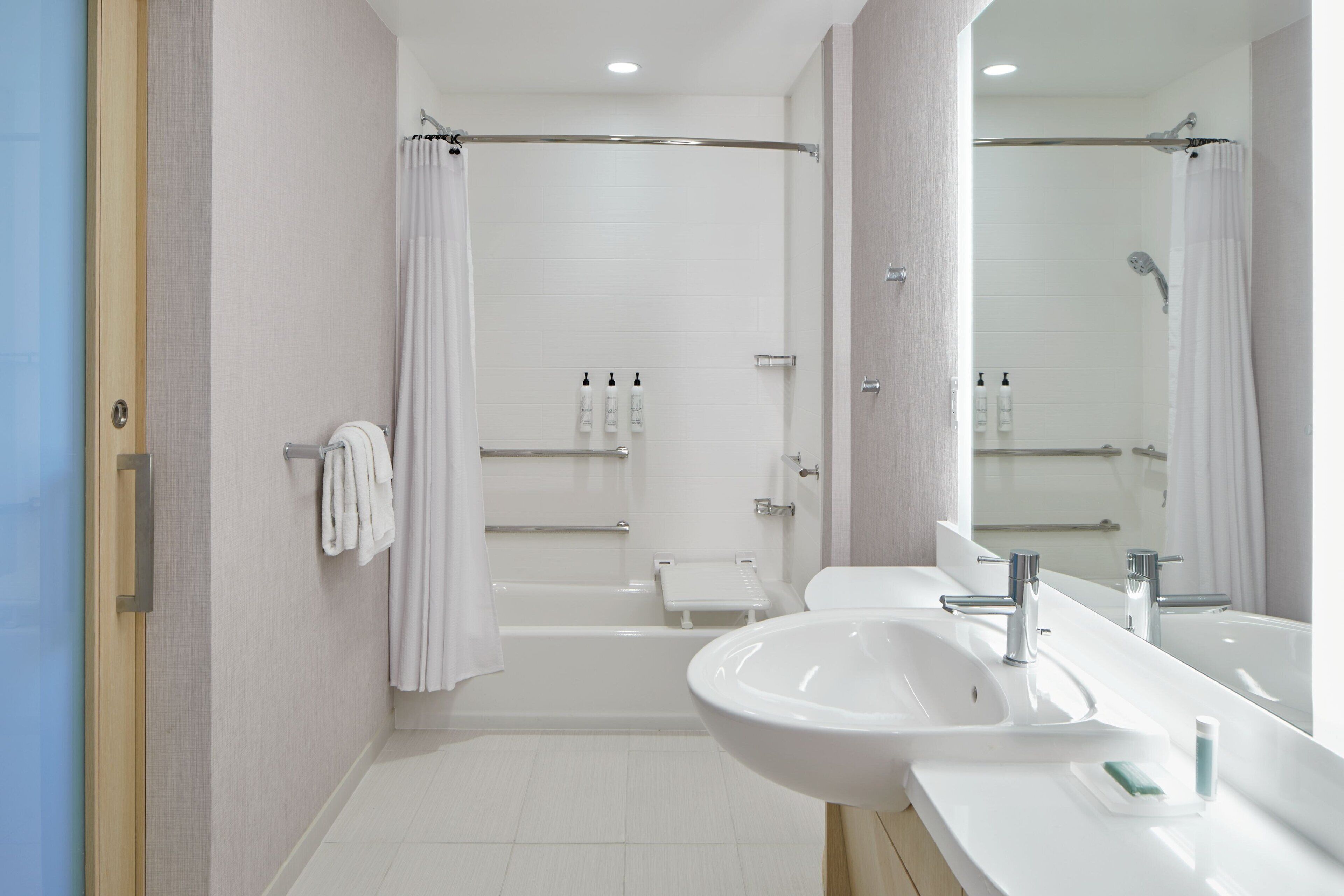 A modern bathroom with a bathtub, a large mirror, and a sink.
