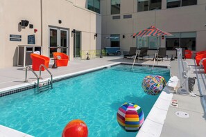 Une piscine équipée de chaises longues et de parasols, d’un toboggan aquatique, ainsi qu’un espace aménagé au bord de la piscine avec une poubelle et un panneau d’information.