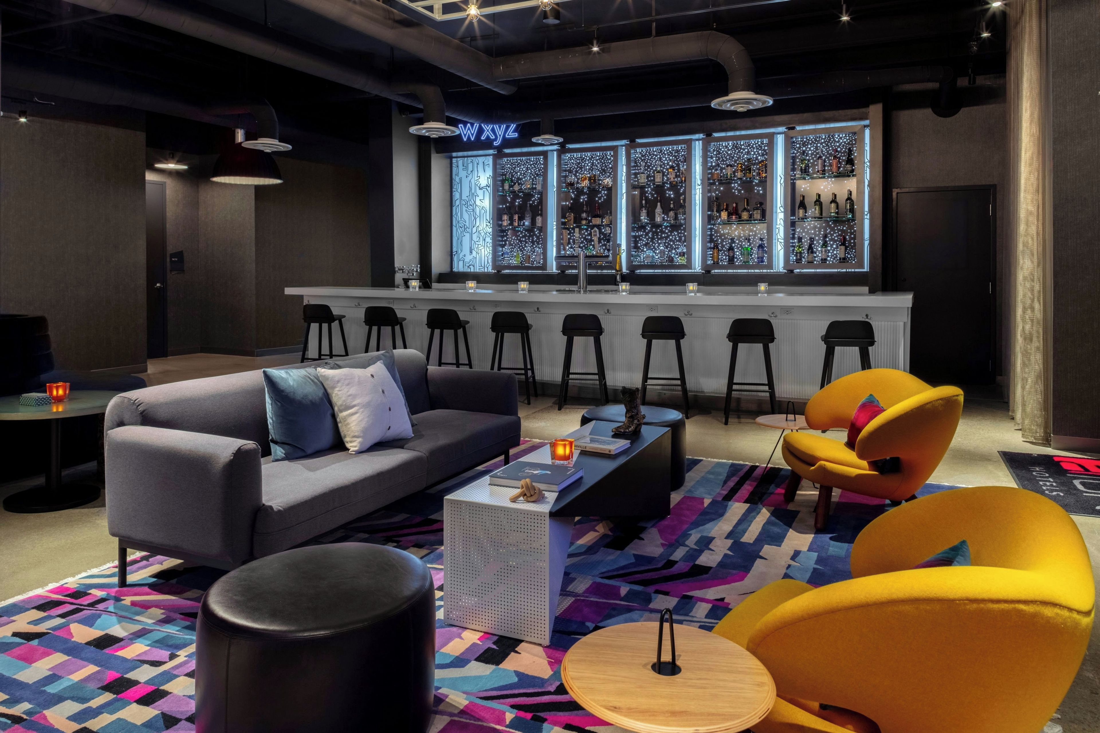 Una zona de bar con mostrador, taburetes y un área de estar con sofá y sillas.