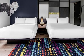 Ein Doppelbett mit weißer Bettwäsche, ein Nachttisch mit Lampe und ein farbenfroher Teppich mit Muster.