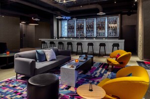 Un espacio lounge moderno con barra, sofás y taburetes.