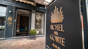 The exterior of Hotel del Conte with a modern facade, a glass entrance, and a potted plant outside. - Hotel del Conte (Laveno Mombello)