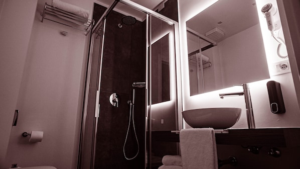 A modern bathroom with a glass-enclosed shower, a sink with a mirror above it, and a towel rack.