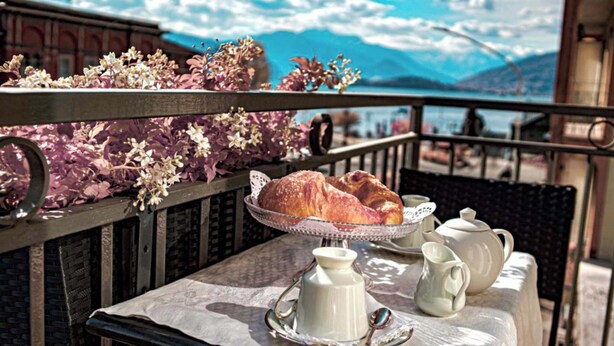 A balcony with a table set for breakfast, including croissants and a teapot. - Hotel del Conte (Laveno Mombello)