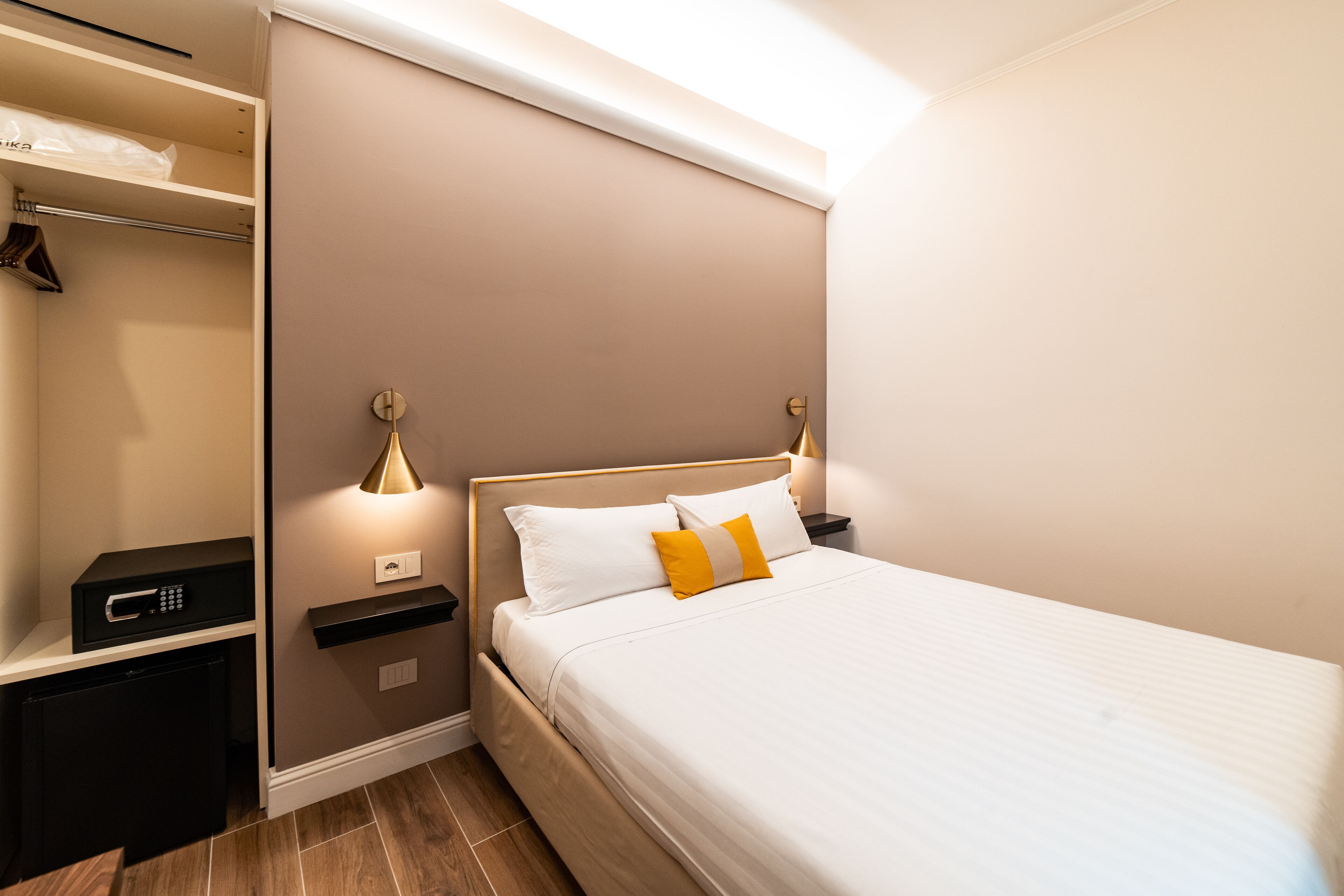 A neatly arranged hotel room with a bed, bedside tables, a small desk, and a wardrobe.