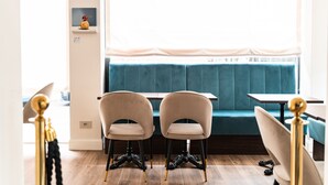 A seating area with two chairs and a table, a blue cushioned bench, and a window with a sheer curtain. - Hotel del Conte (Laveno Mombello)