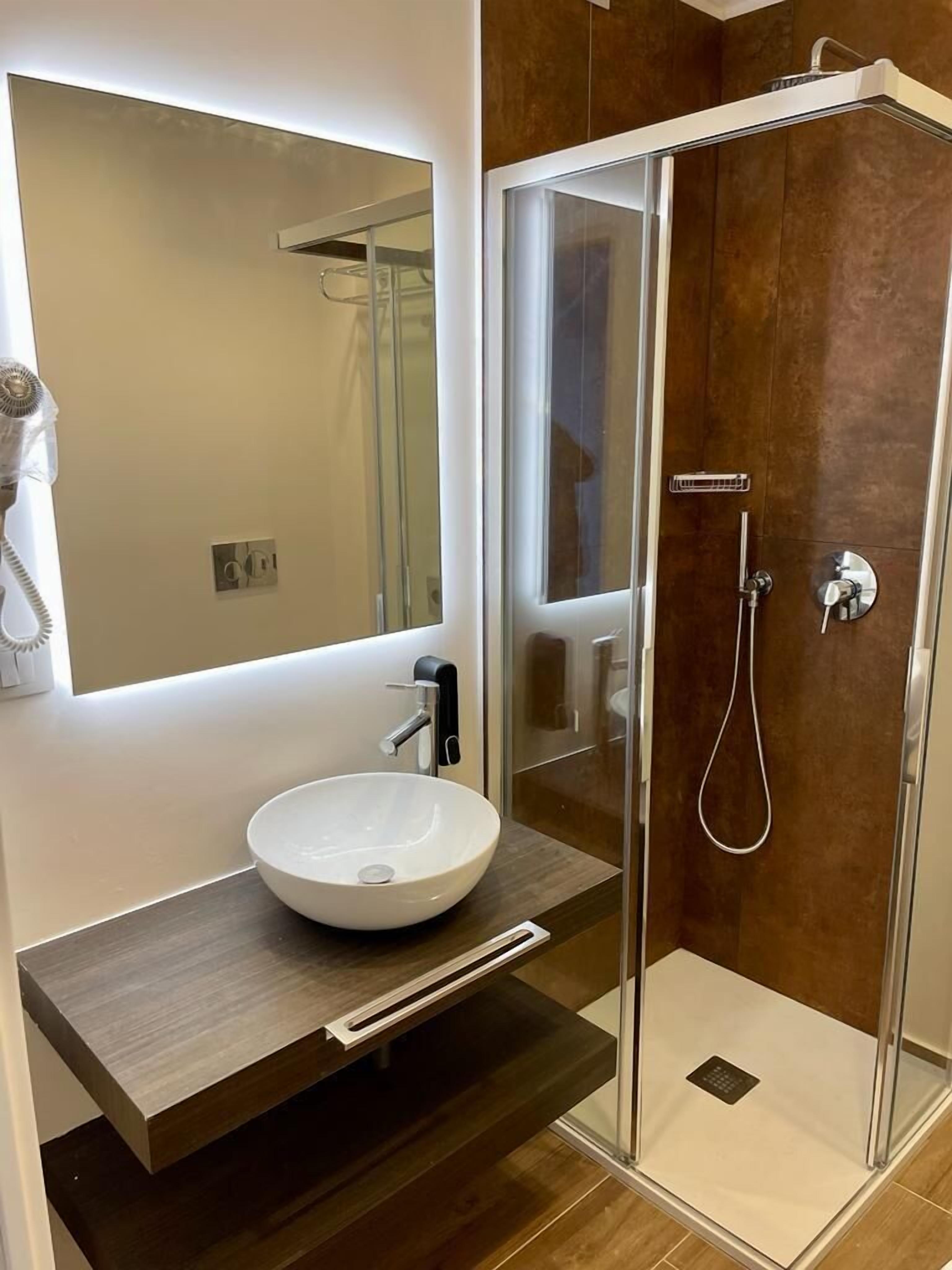 Une salle de bain moderne avec une douche à parois de verre, un lavabo blanc et un miroir au-dessus du meuble-lavabo.
