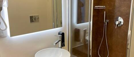 Une salle de bain moderne avec une douche à parois de verre, un lavabo blanc et un miroir au-dessus du meuble-lavabo.