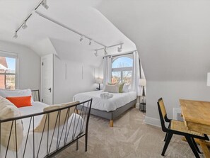 Cozy retreat with a large bed, dining table, and natural light pouring in through the window.
