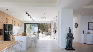 A modern kitchen with wooden cabinets, a central island, and a statue. - 100m2 heated pool, absolute privacy and mesmerising views! (Rethymno)