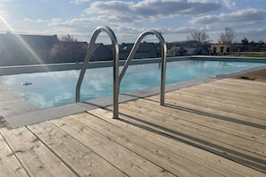 Una piscina con scalette in metallo e un pontile in legno.