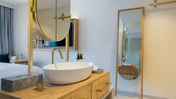 A modern bathroom with a large oval sink, gold faucets, and a wooden vanity.