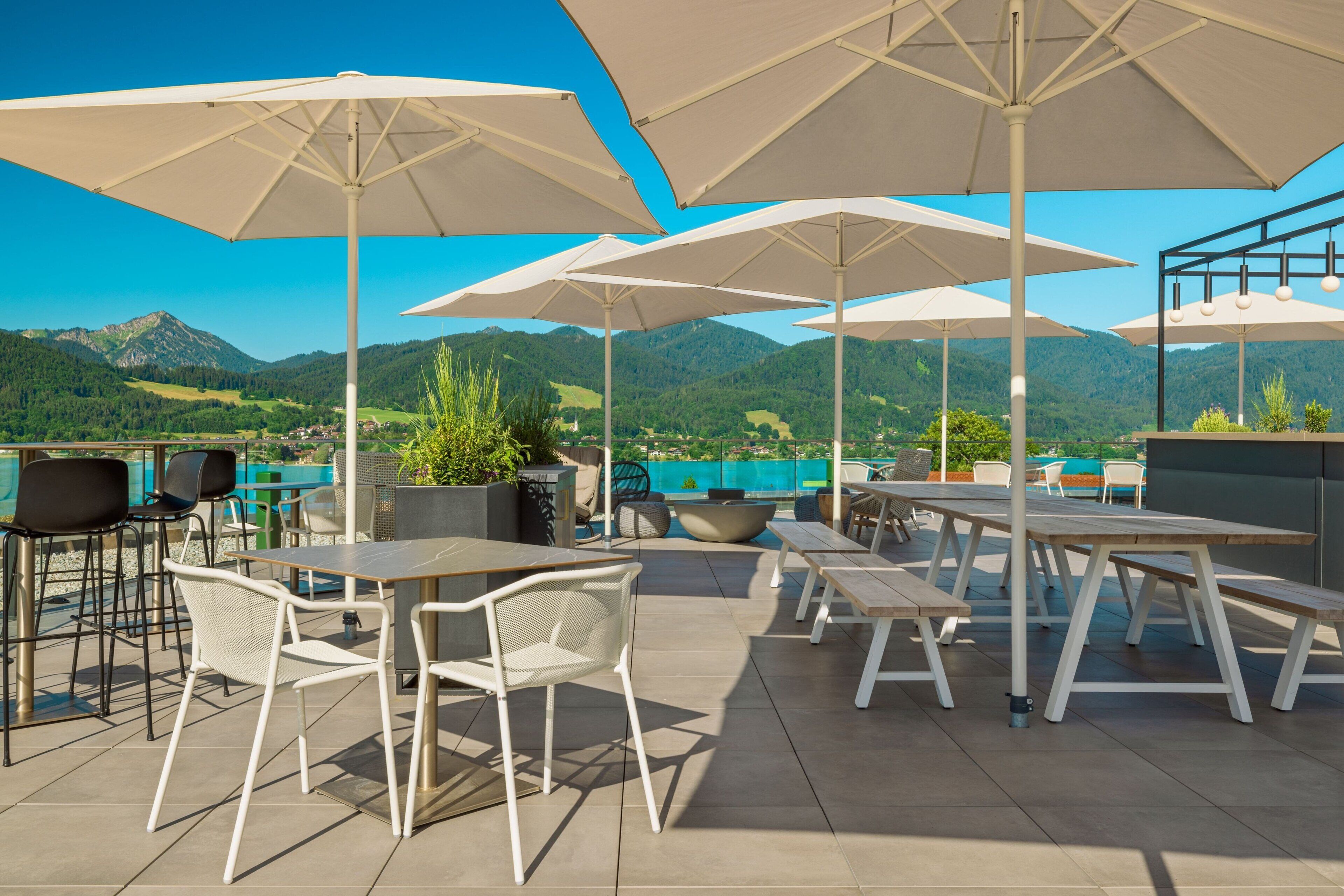 An outdoor patio with tables and chairs, large umbrellas, and a scenic mountain view.