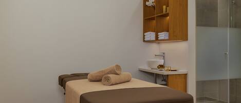 Un baño moderno con cabina de ducha de vidrio, tocador de madera y cama con toallas.