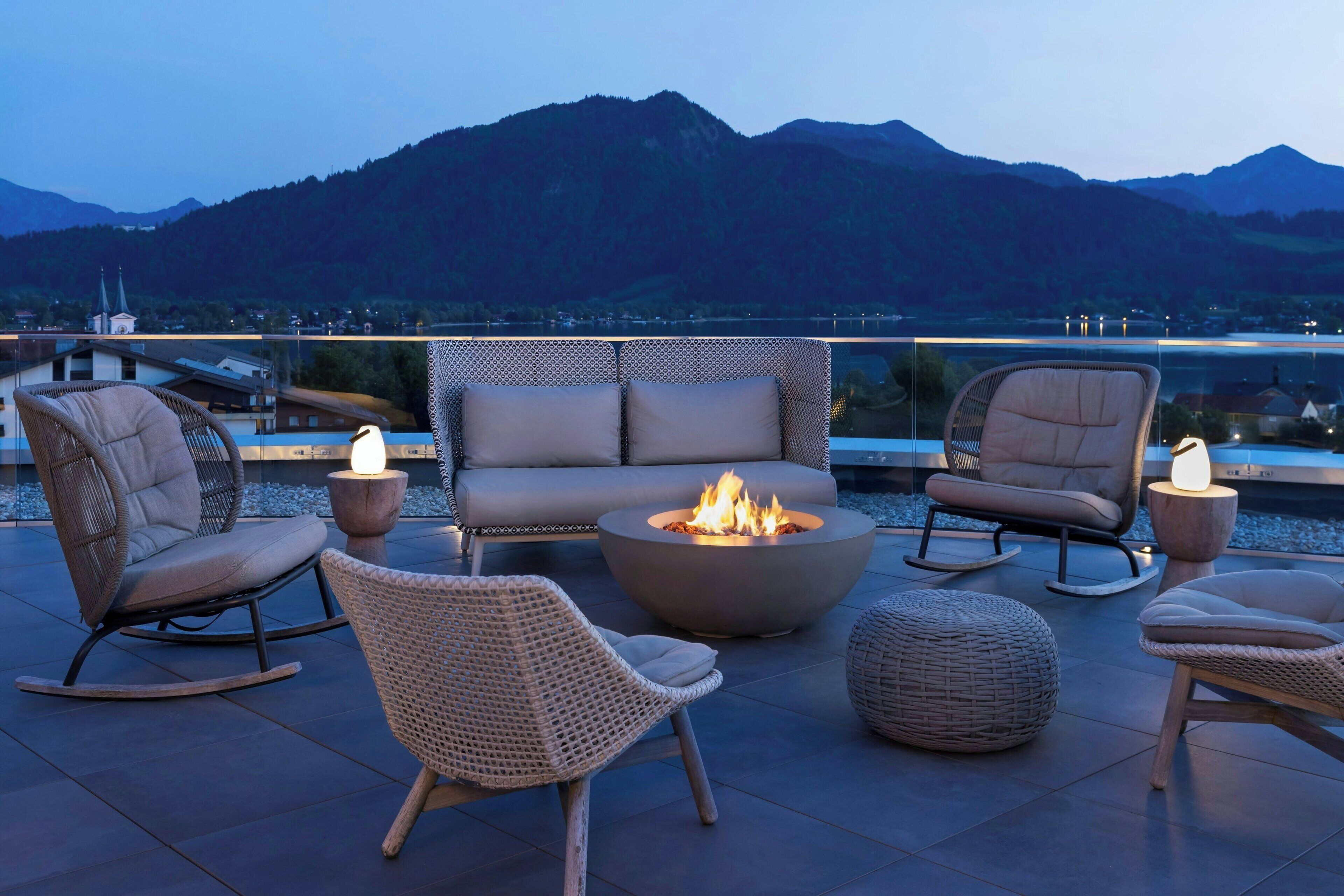 Una terraza con mobiliario de mimbre, una chimenea y vistas a las montañas.