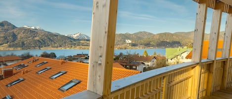A wooden balcony with a view of a lake and mountains.