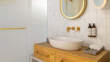 Ein Badezimmer mit einem weißen Waschbecken, goldenen Armaturen und einer Wand aus Marmorfliesen.