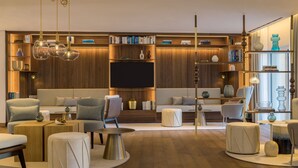 A modern living room with a large flat-screen TV, wooden shelving, and a variety of seating options. - A-ROSA Tegernsee (Tegernsee)