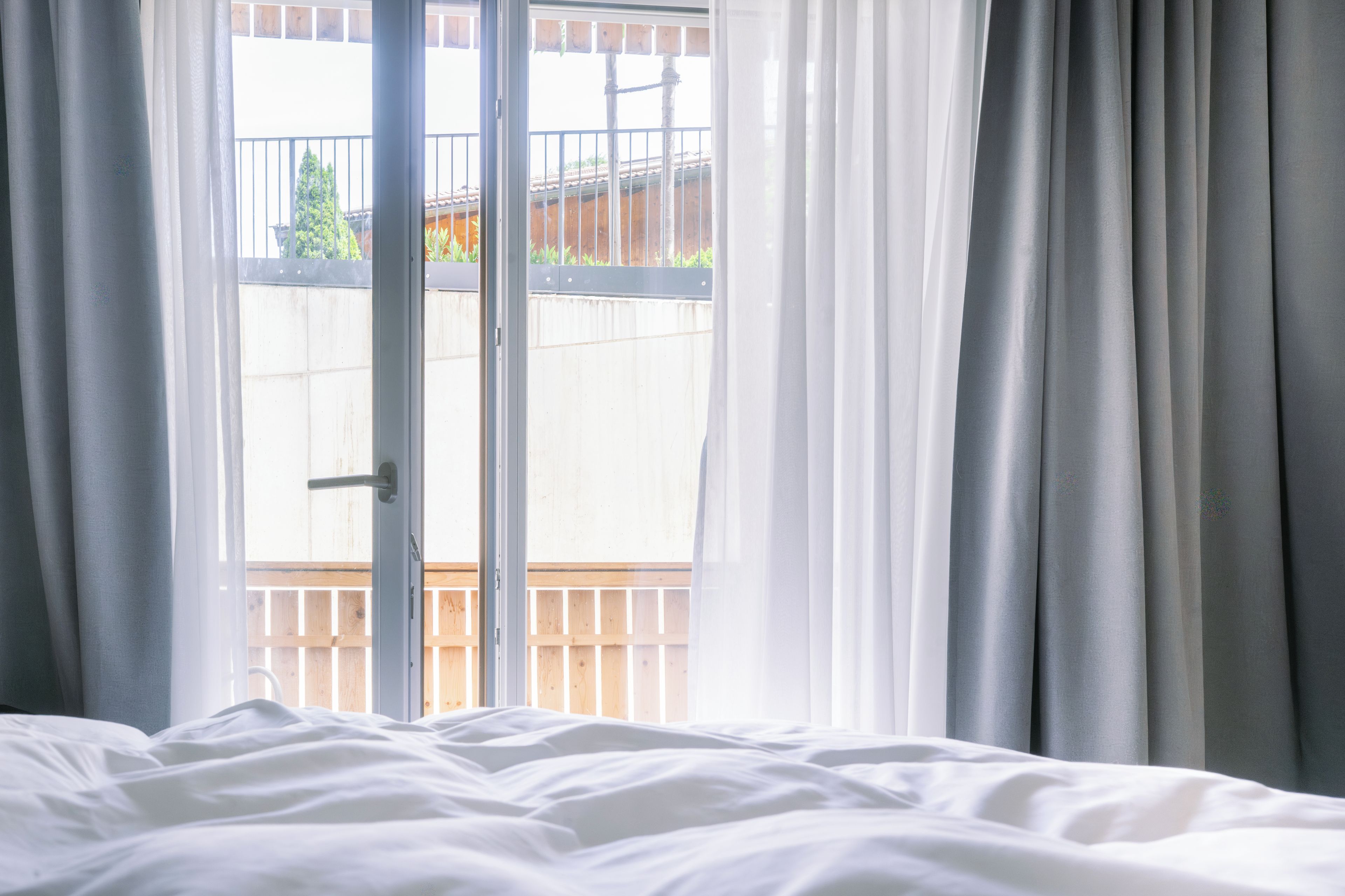 Una habitación con una cama, un ventanal corredizo y vistas a un balcón con barandilla.