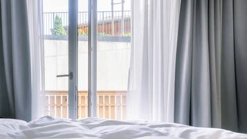 Una habitación con una cama, un ventanal corredizo y vistas a un balcón con barandilla.