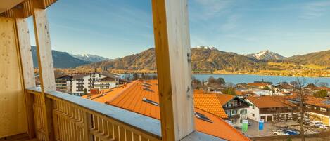 A wooden balcony with a view of a town, mountains, and a lake.