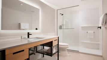 Une salle de bain moderne avec un grand miroir, un lavabo, des toilettes et une douche à parois de verre.