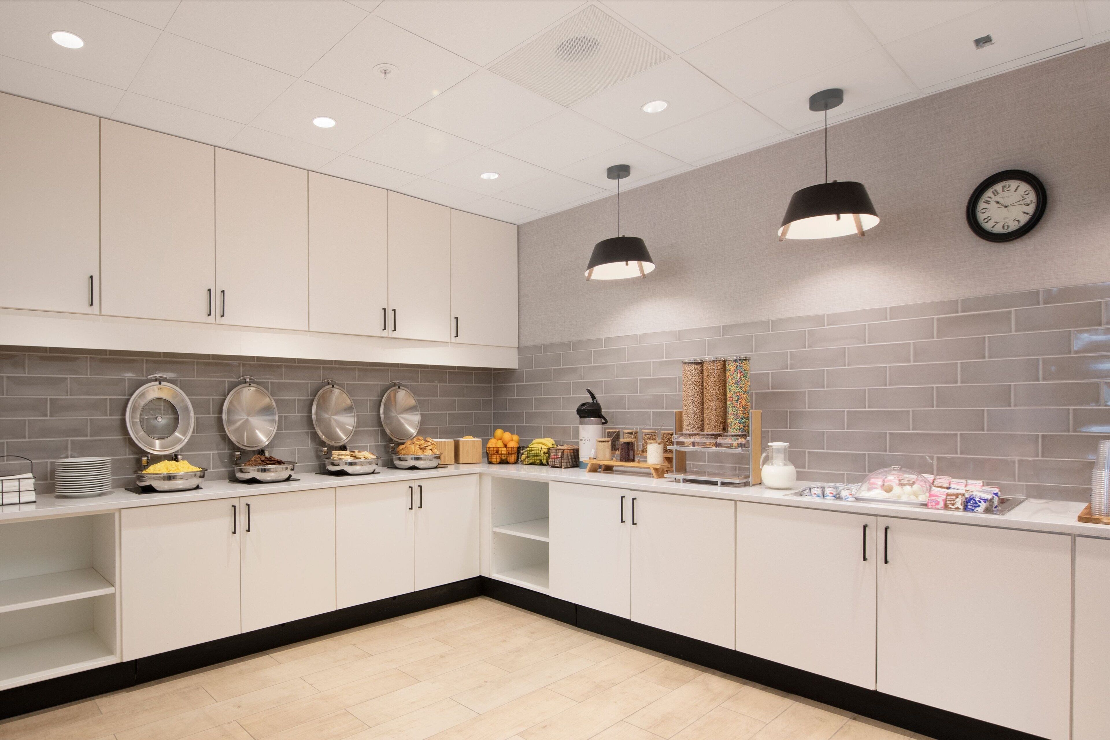 A modern kitchen with white cabinets, a brick backsplash, and pendant lighting.