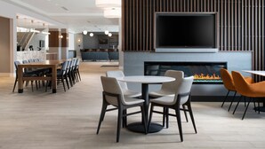 Un salon moderne doté d’une cheminée, d’un téléviseur à écran plat et d’un coin repas avec chaises et tables.