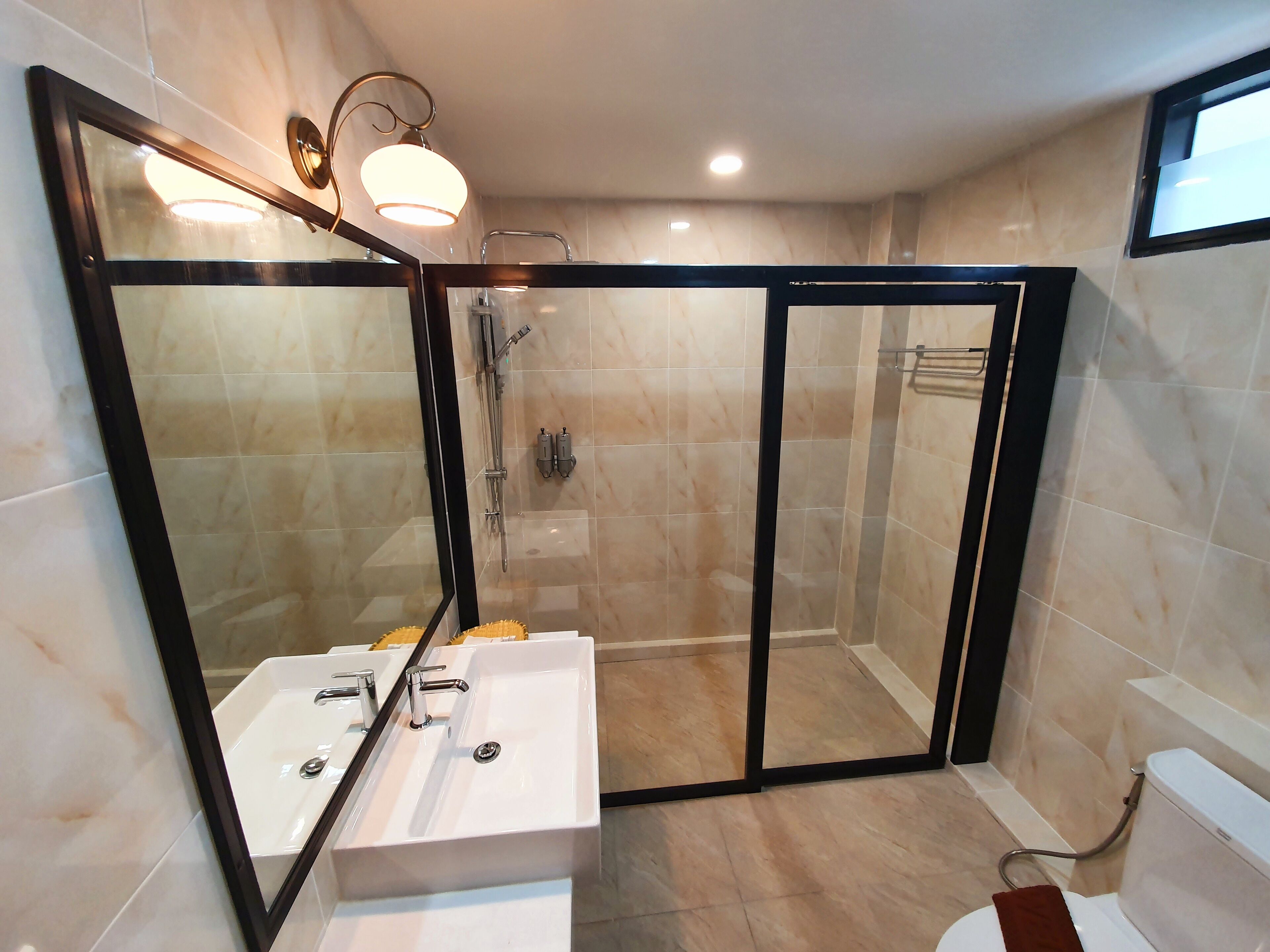 A modern bathroom with a glass-enclosed shower, a white sink with two basins, and a toilet.