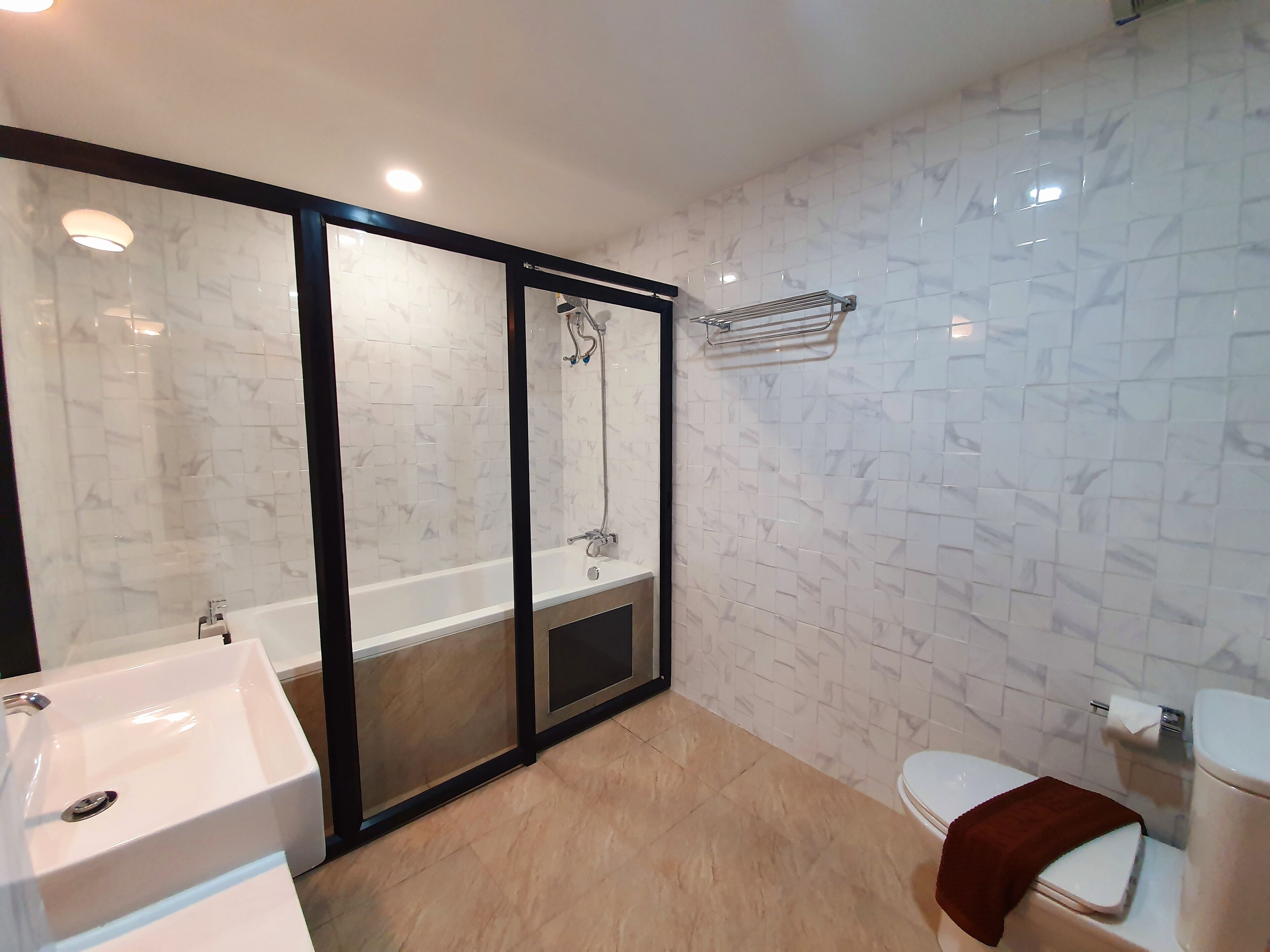 A modern bathroom with a glass-enclosed shower, a white sink, and a toilet.