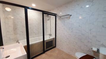 A modern bathroom with a glass-enclosed shower, a white sink, and a toilet.