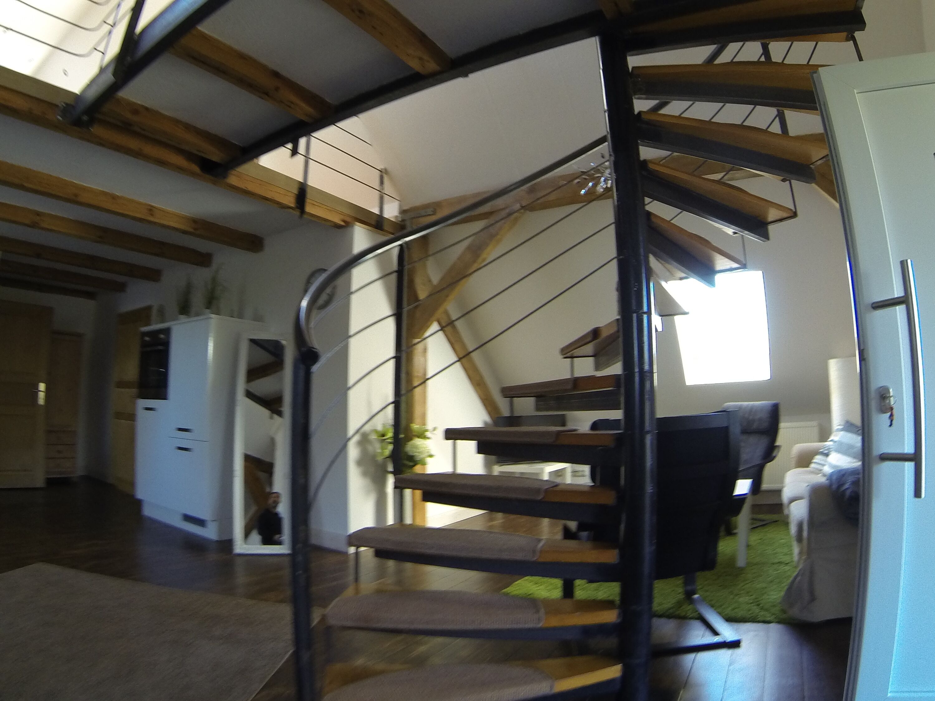 Eine Wendeltreppe mit Holzbalken und modernem Innenraum.