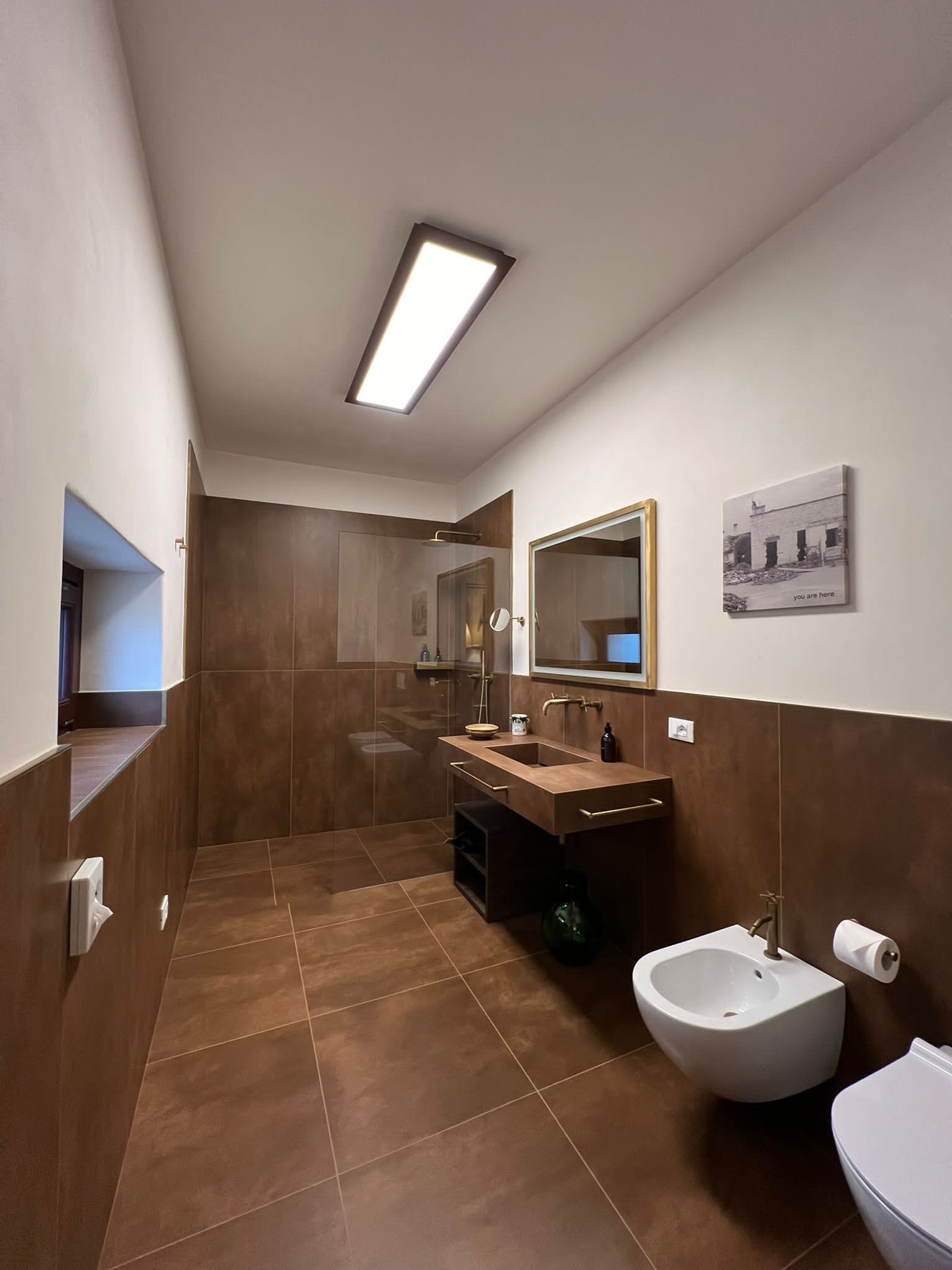 A modern bathroom with a large mirror, a bidet, and a toilet.