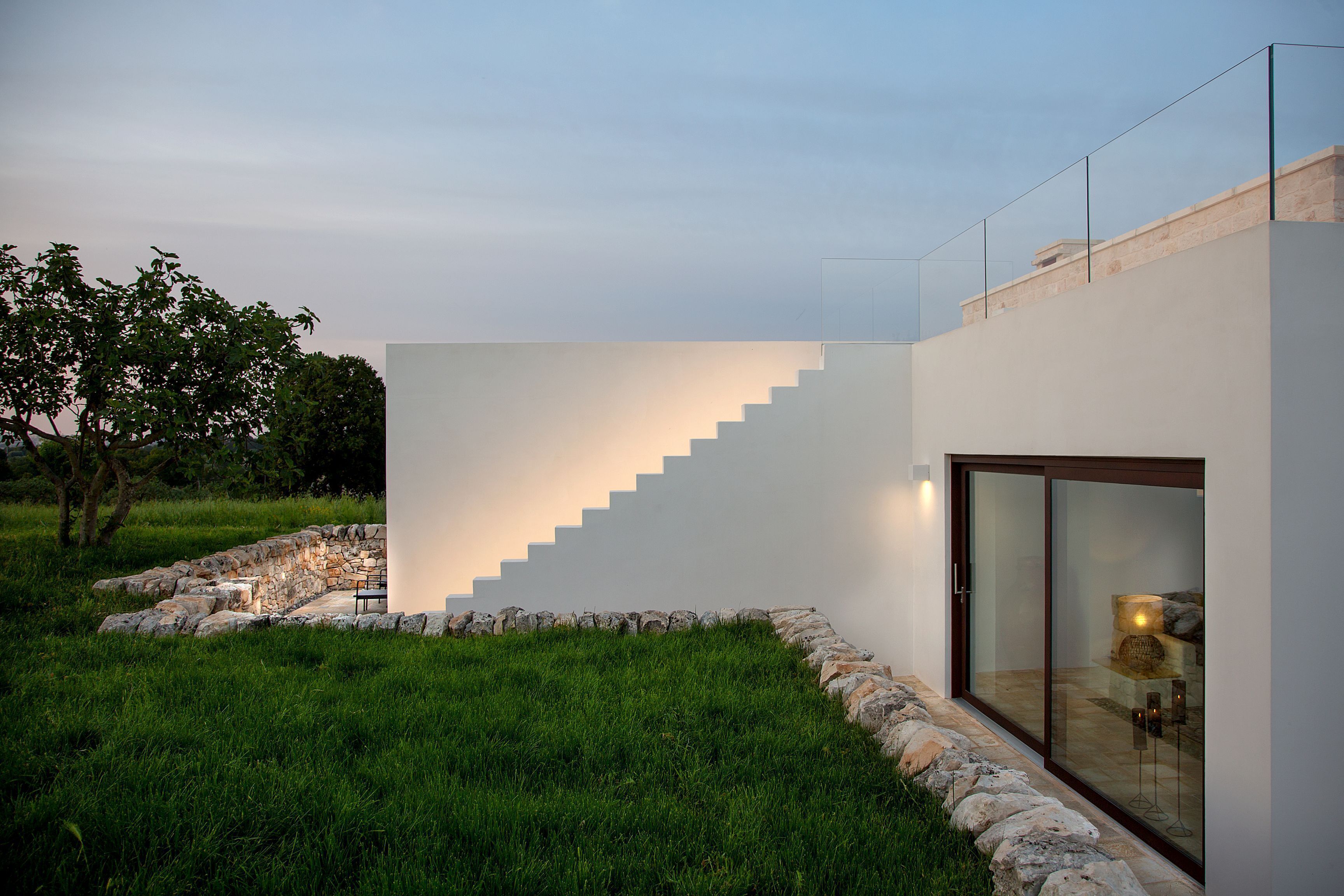 A modern building with a glass door and a staircase leading to a second level.