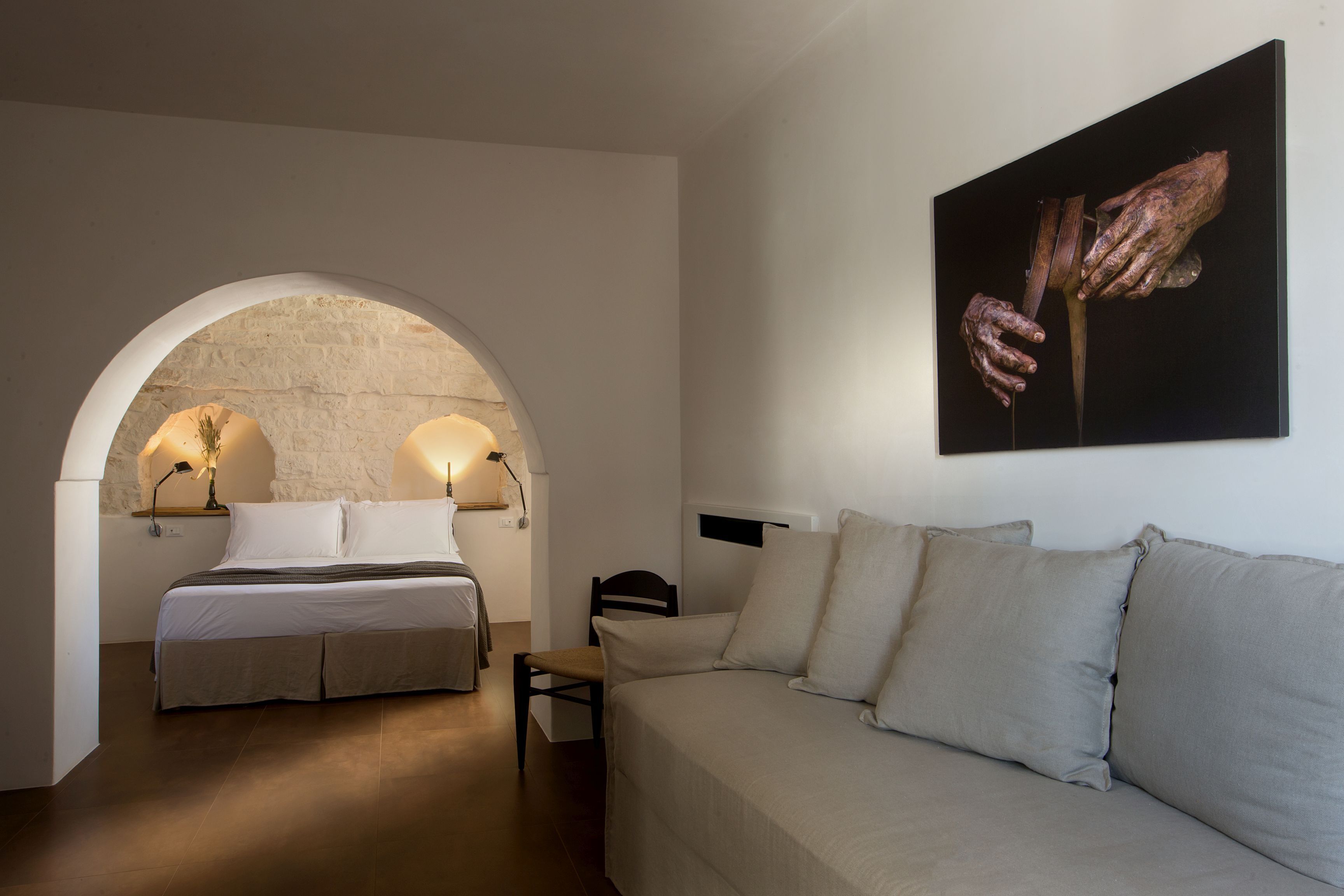 Une chambre avec un lit, un canapé, un tableau et une arche en pierre.