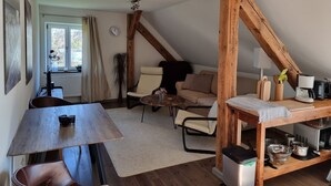 Ein gemütlicher Loft-Wohnbereich mit Essplatz, einer Couch und einer Kaffeestation.