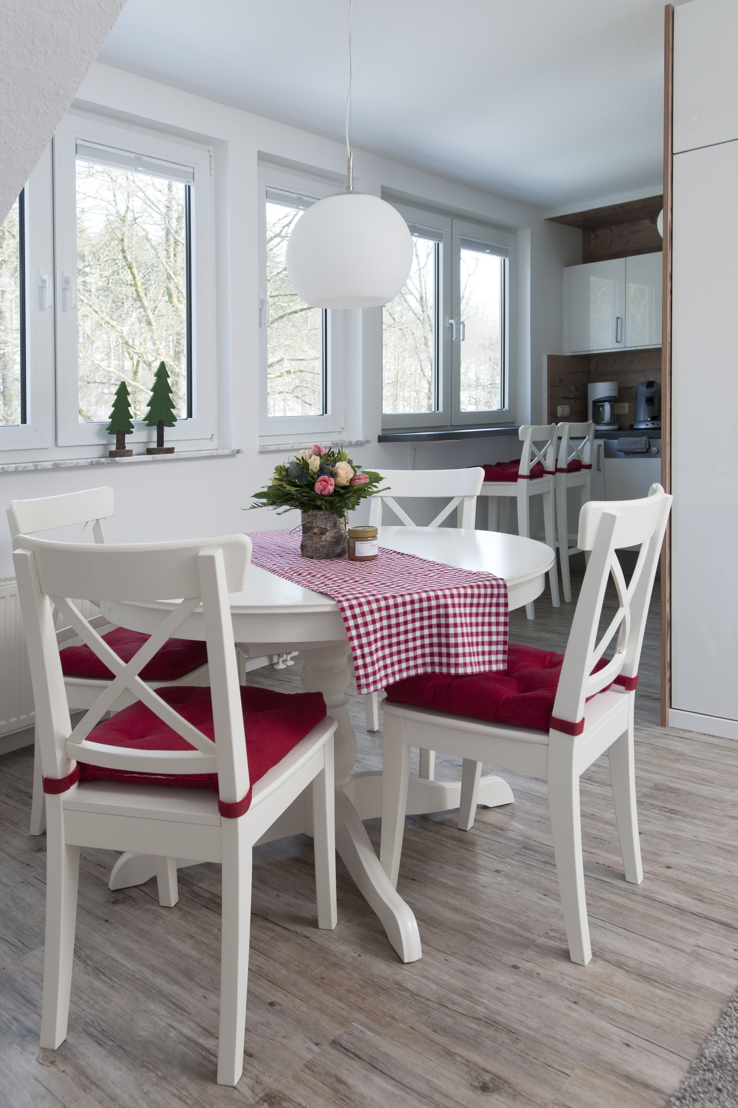 A dining area with white chairs and a table covered by a checkered tablecloth.