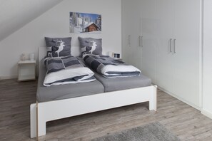 Une chambre à coucher moderne avec un lit, des tables de chevet et une armoire.