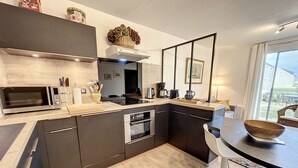 A modern kitchen with a microwave, oven, and sink. There is a dining area with a table and chairs.