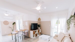 Un salon moderne comprenant un canapé, un téléviseur, une table à manger, des chaises et un ventilateur de plafond.