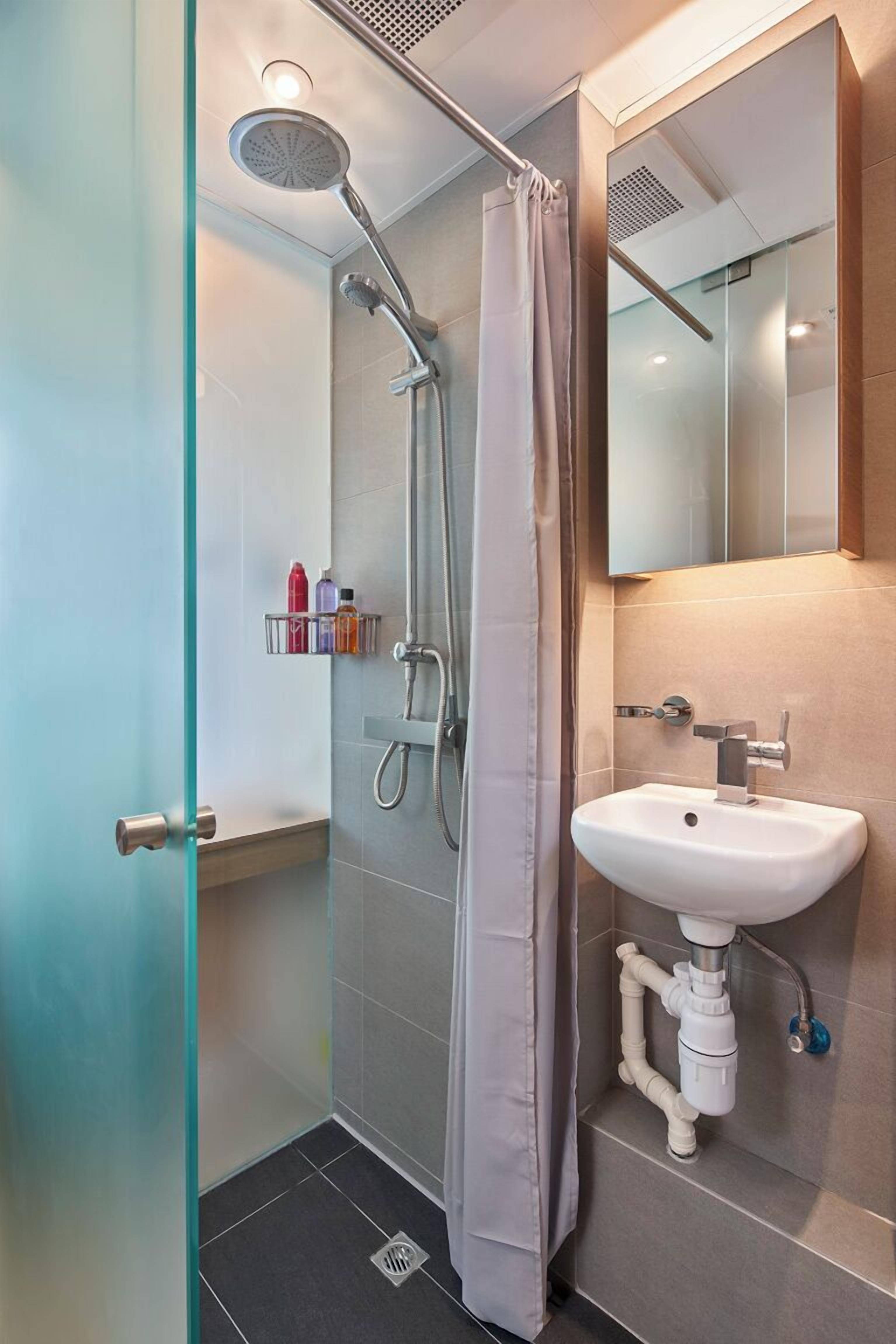 Un baño moderno con cabina de ducha de vidrio, un lavabo blanco y un espejo encima.