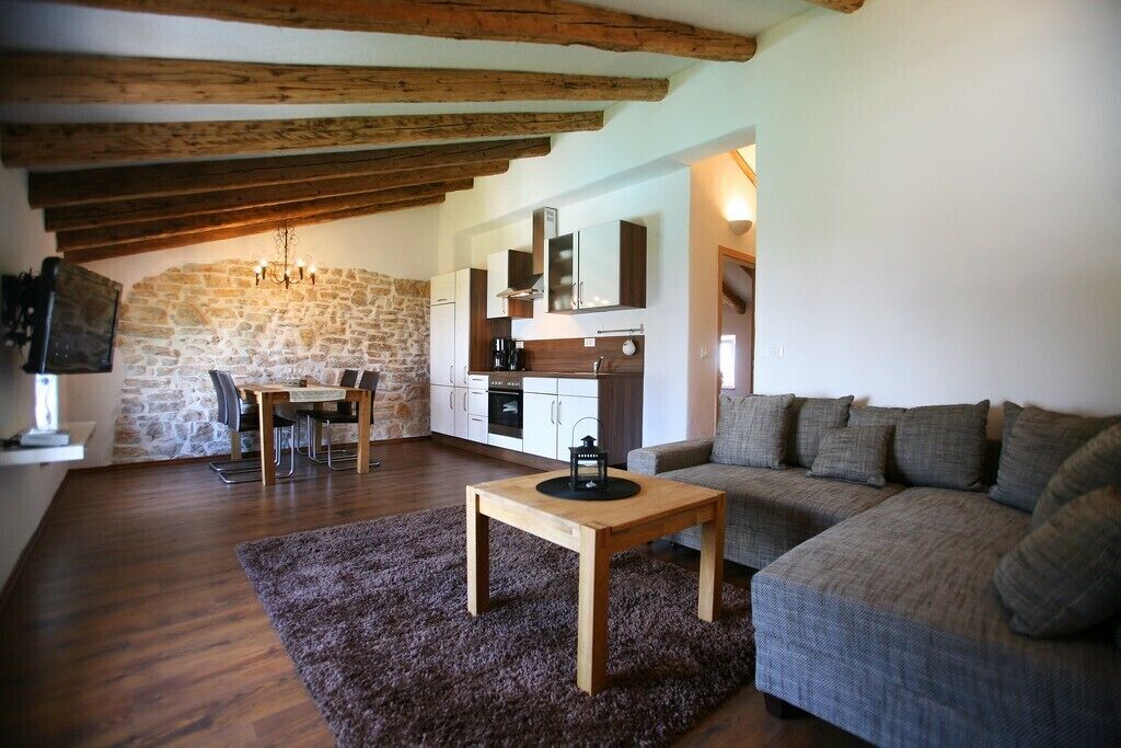 A cozy living room with a wooden table, a sofa, and a stone wall.