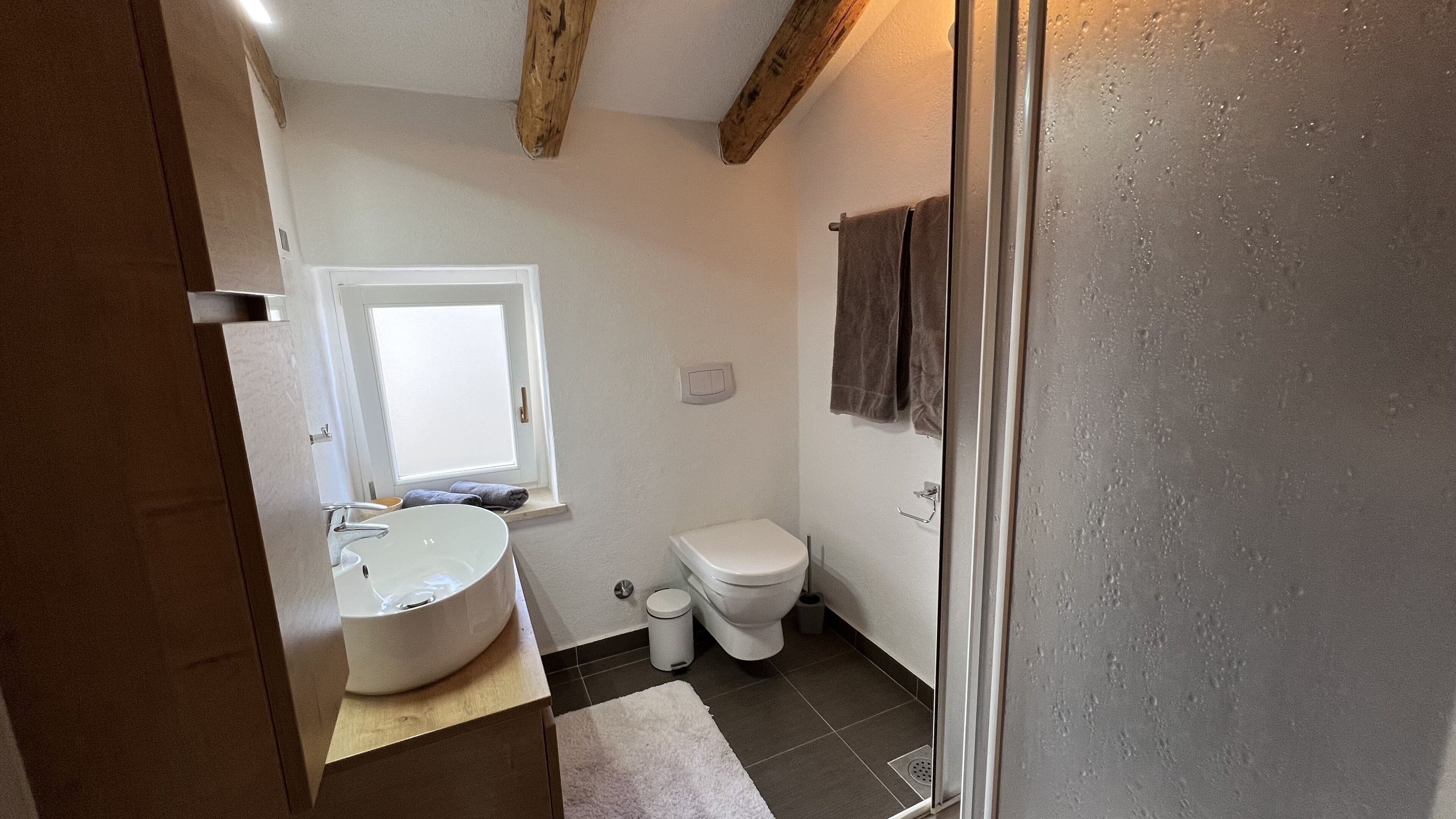 Une salle de bain avec un lavabo blanc, des toilettes et une fenêtre.