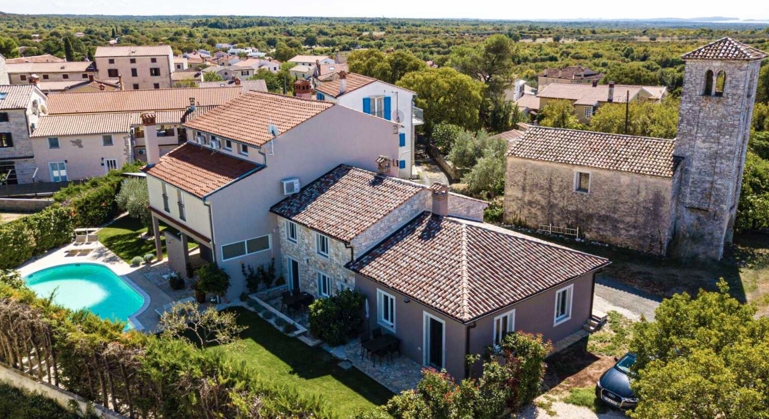 A residential area with a stone tower, a swimming pool, and houses with red-tiled roofs.