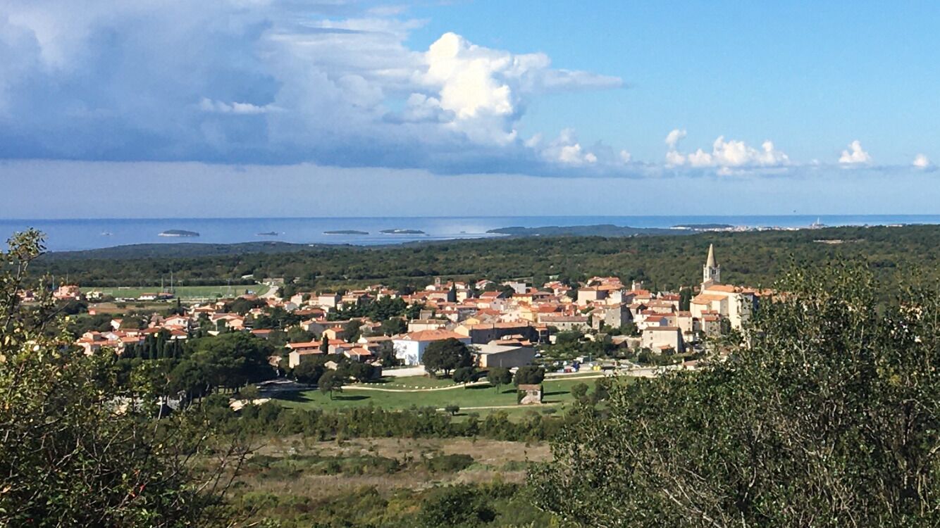 A coastal town with a prominent church, green spaces, and a view of the sea.