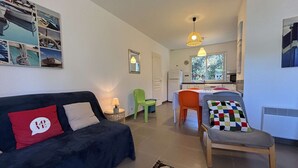 Un espacio habitable compacto con sofá, sillas, una mesa de comedor y una zona de cocina.