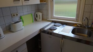 Une cuisine de taille réduite, équipée d’une cuisinière intégrée, d’un évier et d’une fenêtre.
